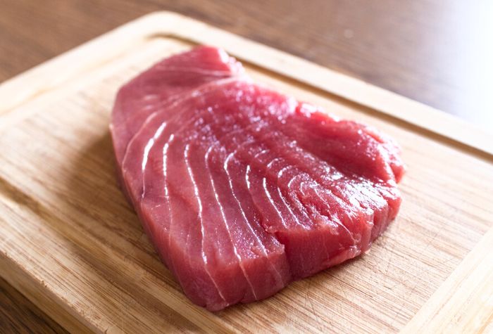 raw tuna steak sitting on chopping board