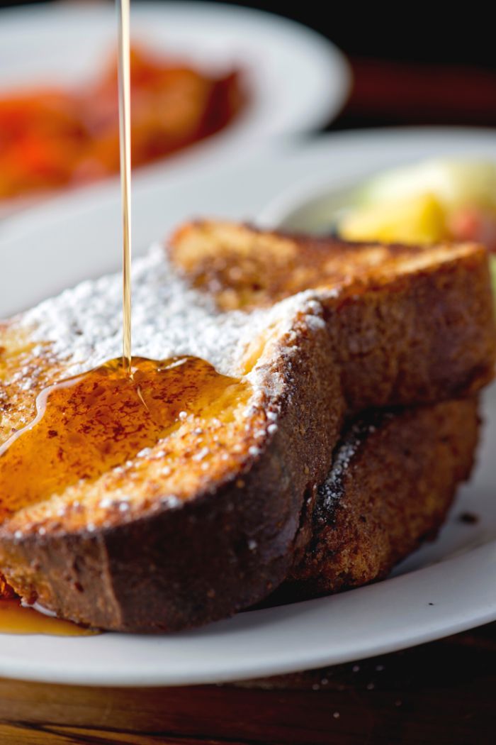 close-up of french toast being topped with maple syrup