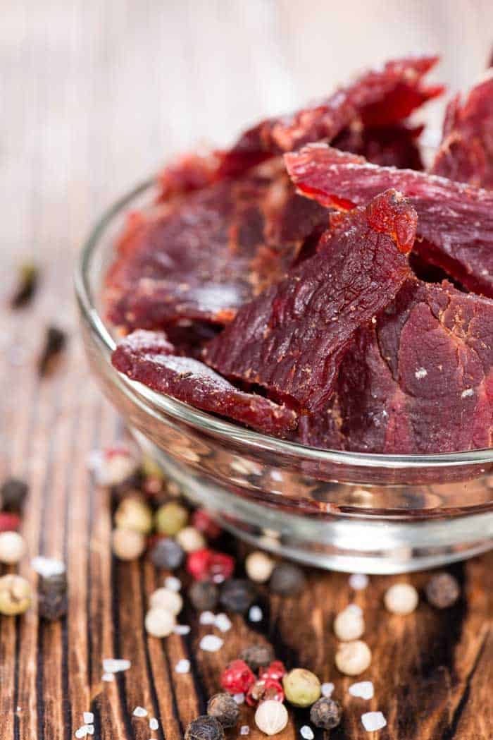 smoked beef jerky on wooden table with pepper corns