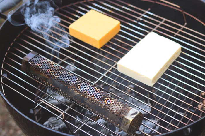 smoking cheddar cheese on charcoal grill grates with lit smoke tube