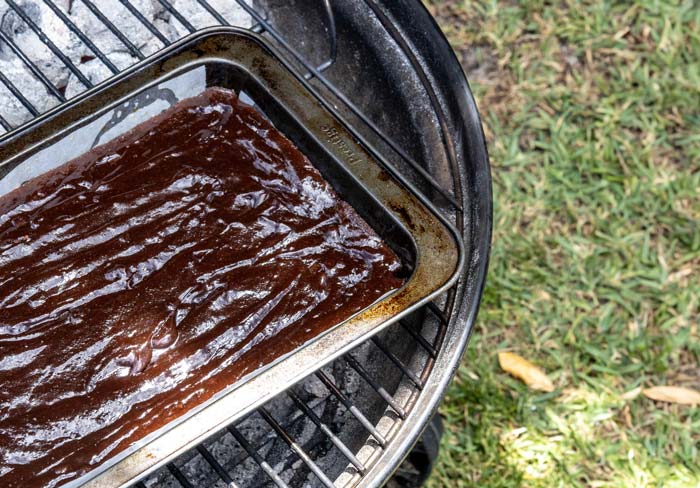 chocolate brownie batter in baking tray on smoker grill grates
