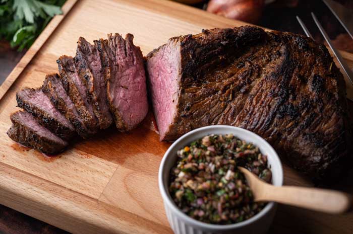 smoked tri tip served on chopping board with chimichurri