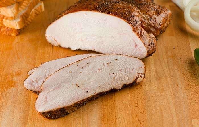 smoked turkey breast sliced on kitchen wood counter