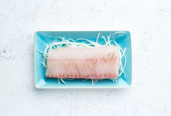 raw walleye fillet presented on blue plate