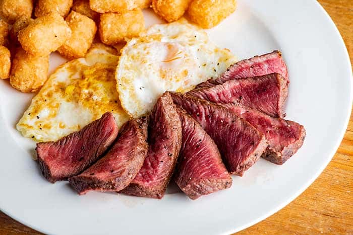 steak medium rare with eggs sunny side up potato hash side dish