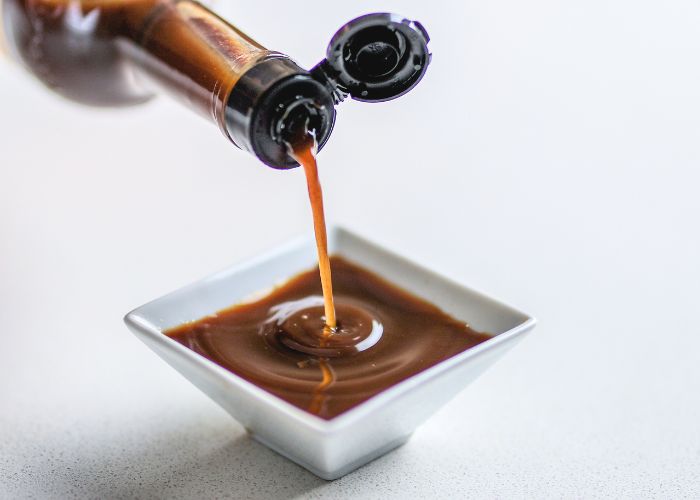 closeup of worcestershire sauce being poured into small serving pot